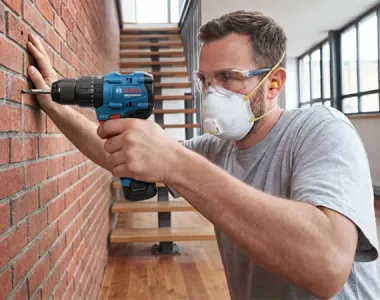 Bosch Promo Image Showing 16V Cordless Drill Used by Worker on Brick Wall